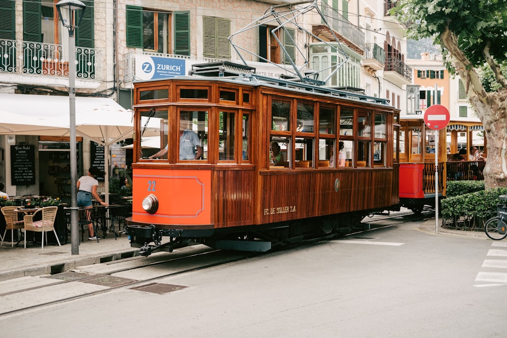 an orange trolley car on a city street