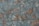 A close-up view of a textured surface resembling natural stone or marble, featuring intricate patterns of veins and mottled patches. The colors are a mix of bluish-grey with warm rust undertones, creating an organic, earthy appearance.