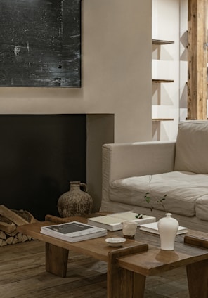 A cozy living room corner featuring a wooden magazine rack beside a small ottoman footrest.
