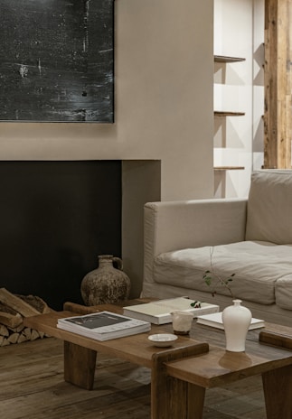 A cozy living room corner featuring a sleek wooden coffee table adorned with a delicate ceramic vase and soft linen cushions.