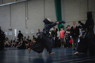 A dynamic photo capturing kendoka in mid-strike during an intense kendo match under traditional dojo lighting.