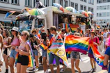Vibrant street parade with people waving flags and confetti flying.