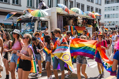 Vibrant street parade with people waving flags and confetti flying.
