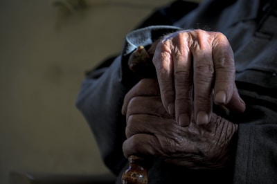 Close-up of hands holding a walking cane with a community park in background.