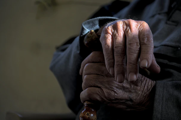 Close-up of a pair of hands gripping a sturdy cane resting on a city bench