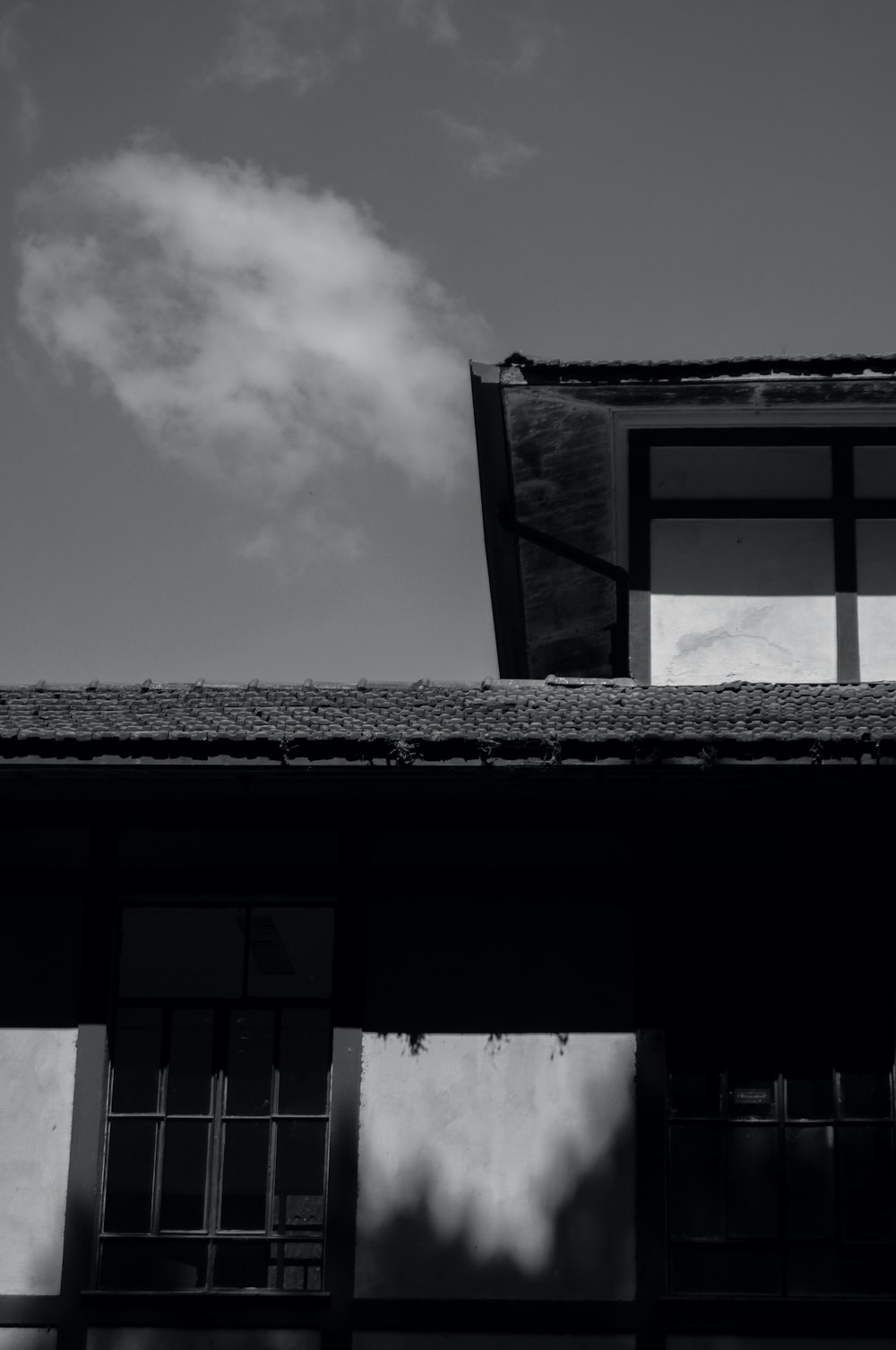 a black and white photo of a building with a sky background
