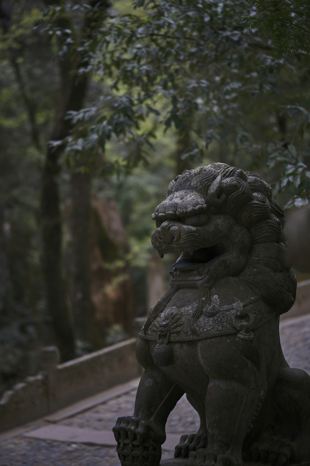 a stone lion statue sitting on a brick walkway