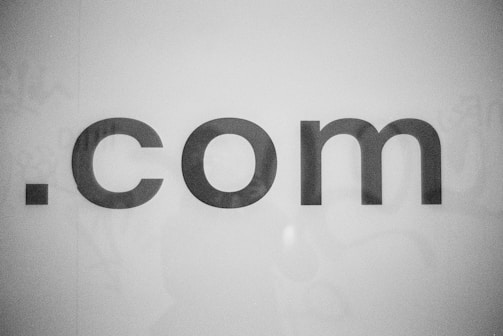 The image features the text '.com' in bold, black lettering against a plain white background. The text appears centered and the font is simple and modern.