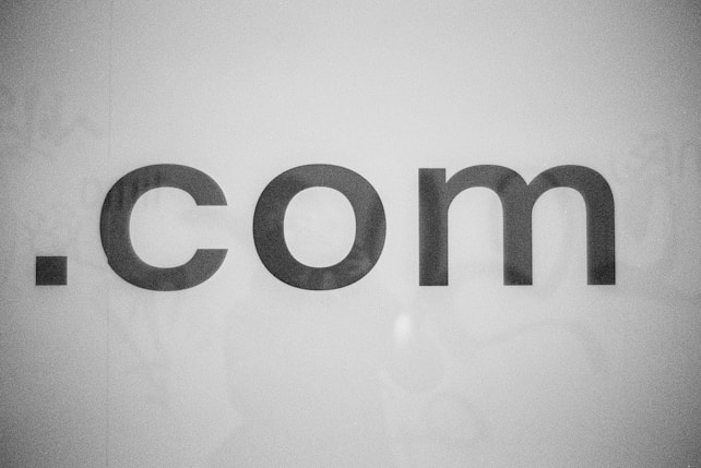 The image features the text '.com' in bold, black lettering against a plain white background. The text appears centered and the font is simple and modern.