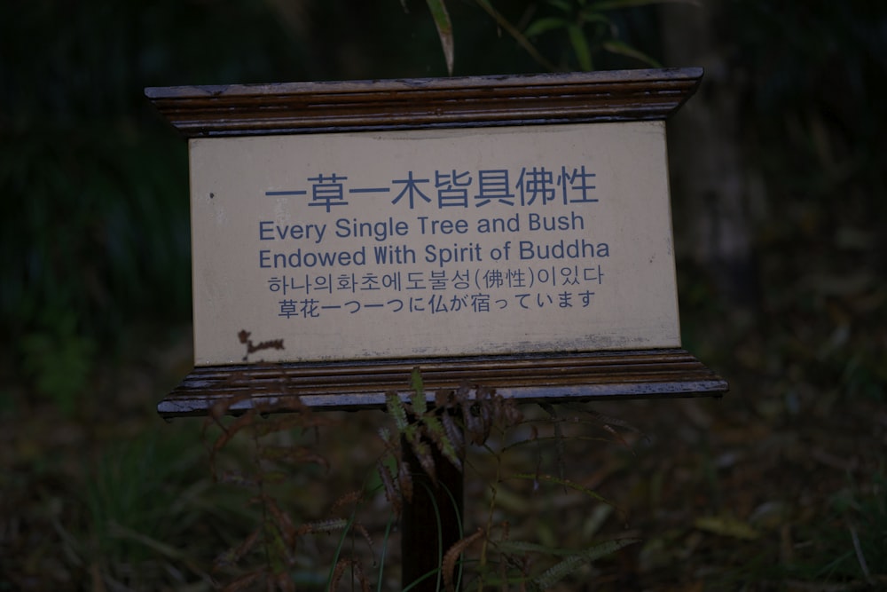 a sign that is in the grass near a bush