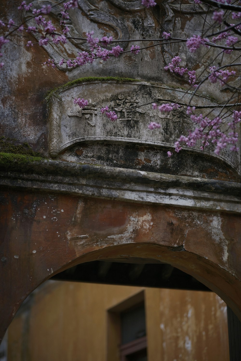 a stone arch with a pink flower on it