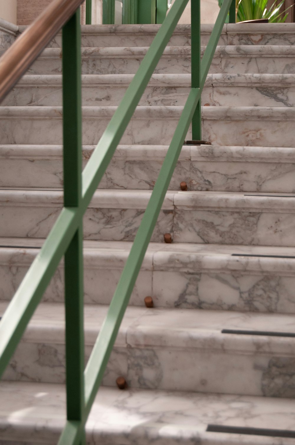 a marble staircase with green handrails in a building