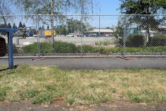 A clean chain link fence surrounding a spacious commercial property under clear skies.