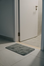 a bathroom rug on the floor in front of a door