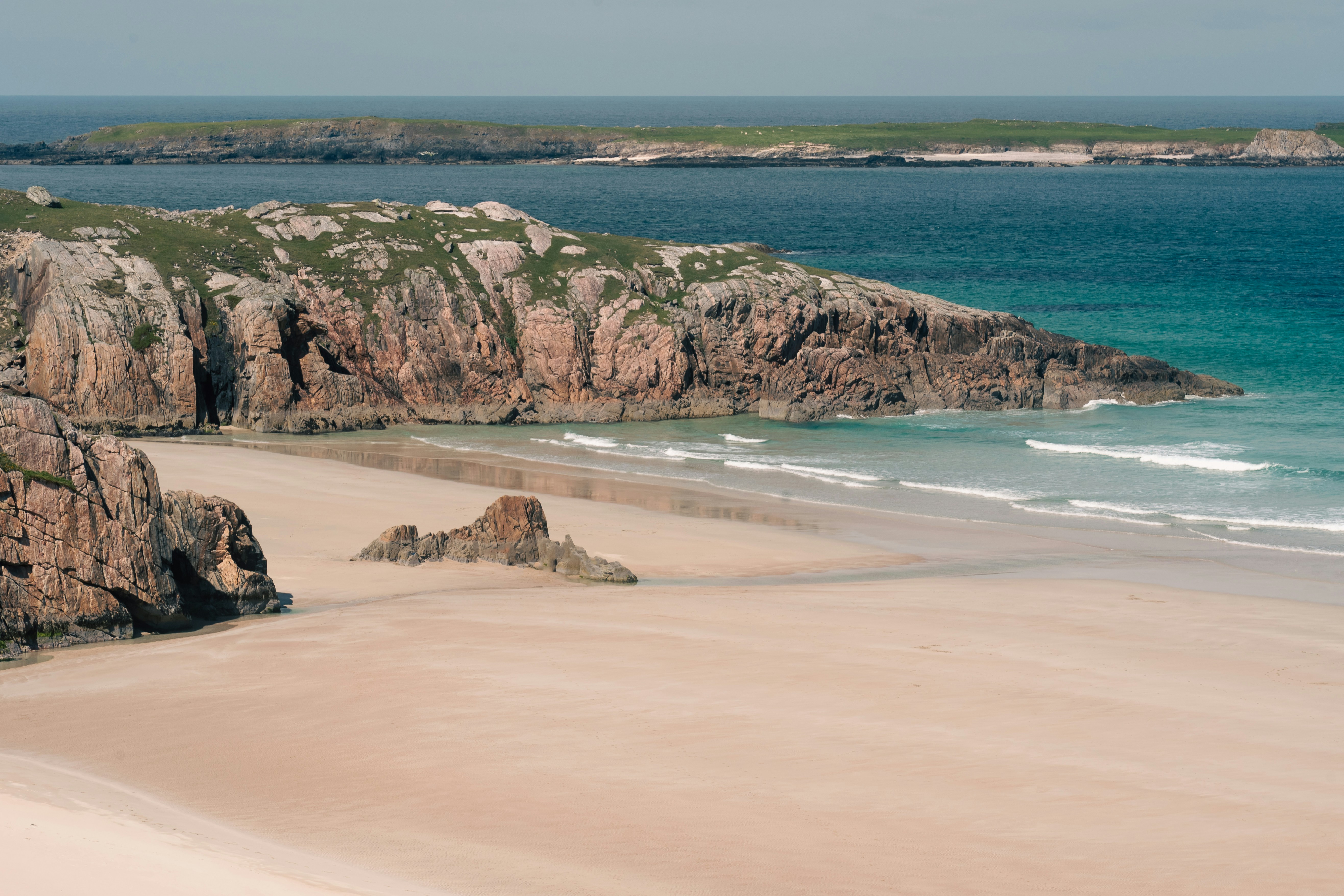 a sandy beach next to a body of water