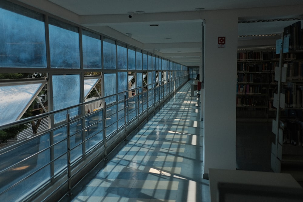 a long hallway with lots of windows next to a book shelf