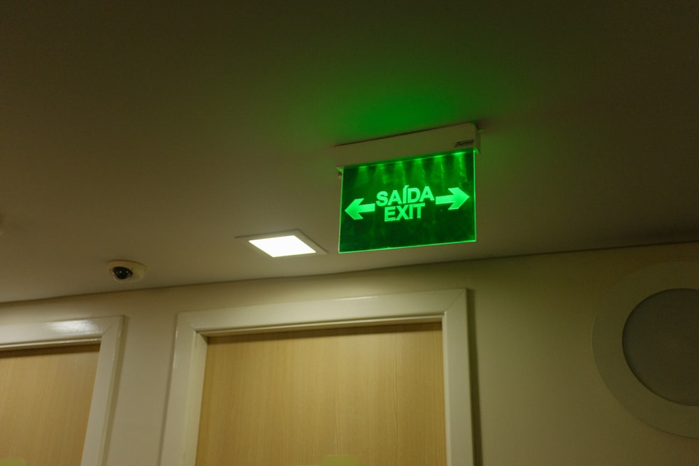 a green exit sign above two closed doors