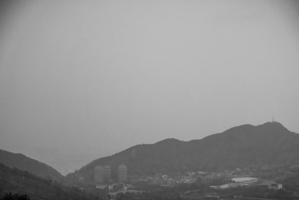 a black and white photo of a city with mountains in the background