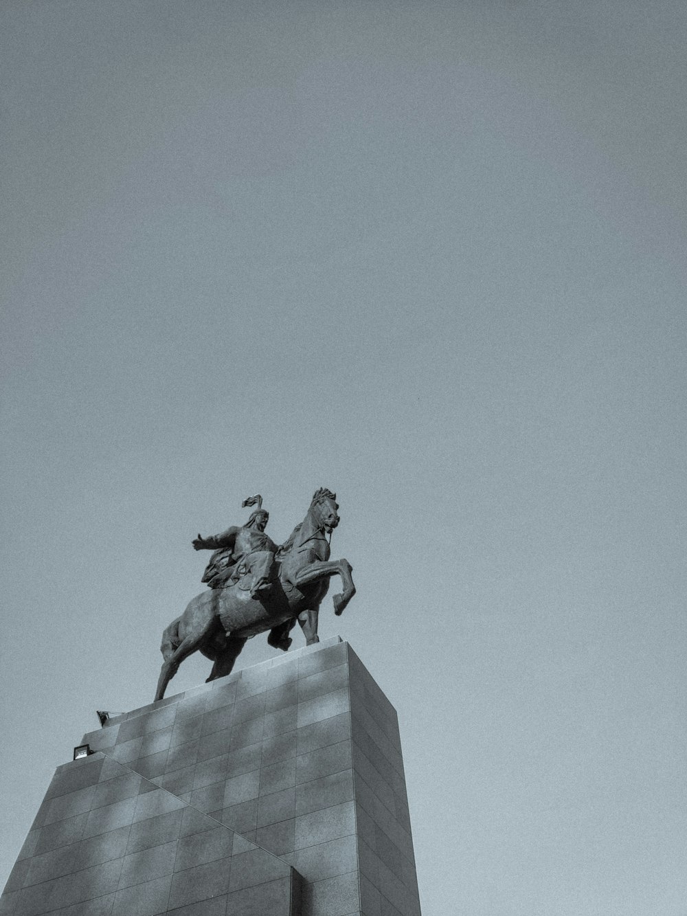 a black and white photo of a statue of a man riding a horse
