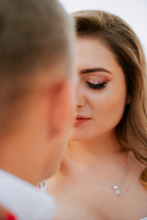 Side profile of a woman with glowing bridal makeup and subtle shimmer eyeshadow.