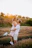 A candid sunlit moment of a couple sharing a joyful embrace in a golden field.