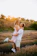 A warm, sunlit portrait of a joyful couple embracing in a golden field.