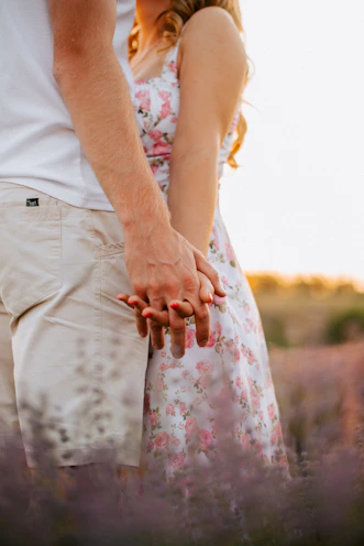 A warm photo of a couple holding hands in a sunlit garden with soft pastel tones.