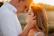 An intimate moment between a couple sharing a quiet laugh under soft terracotta-hued sunset light.