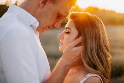 A tender moment of a couple embracing softly at sunset, bathed in warm light.