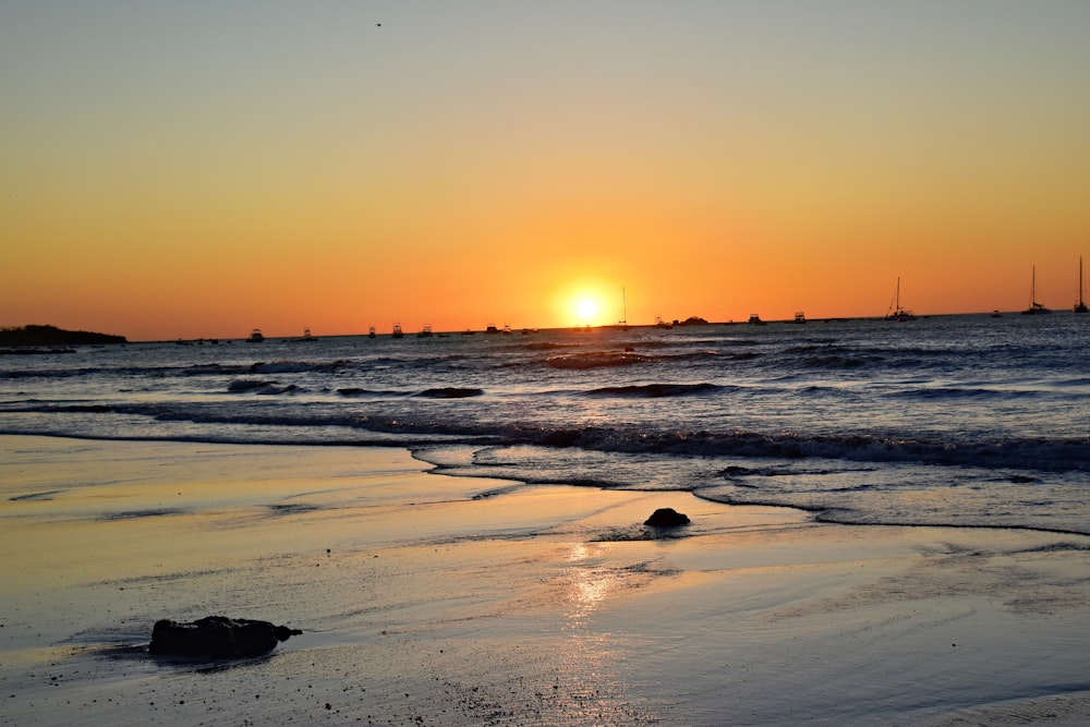 the sun is setting over the water at the beach