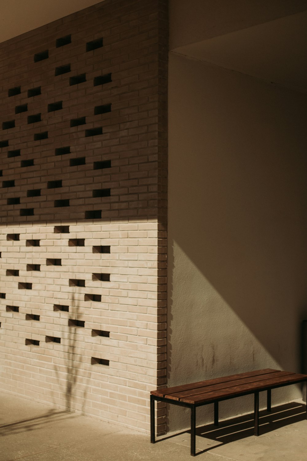 a bench sitting in front of a brick wall