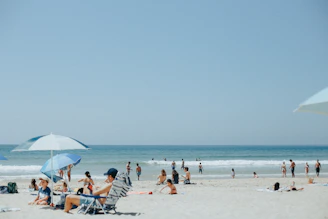 Kids playing on a sandy beach while parents relax nearby under colorful umbrellas.