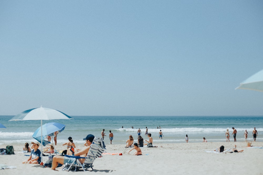 a group of people sitting on top of a sandy beach