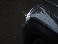 A close-up of a perfectly installed windshield with water droplets glistening in the sunlight.