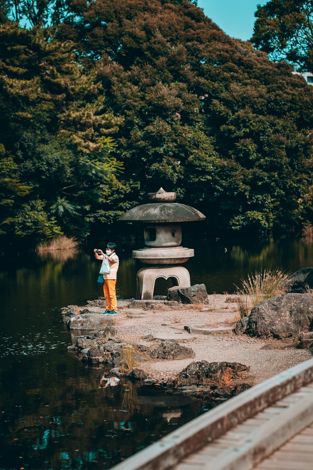 a person taking a picture of a statue in a pond