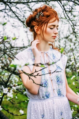 a woman in a white dress standing in a tree