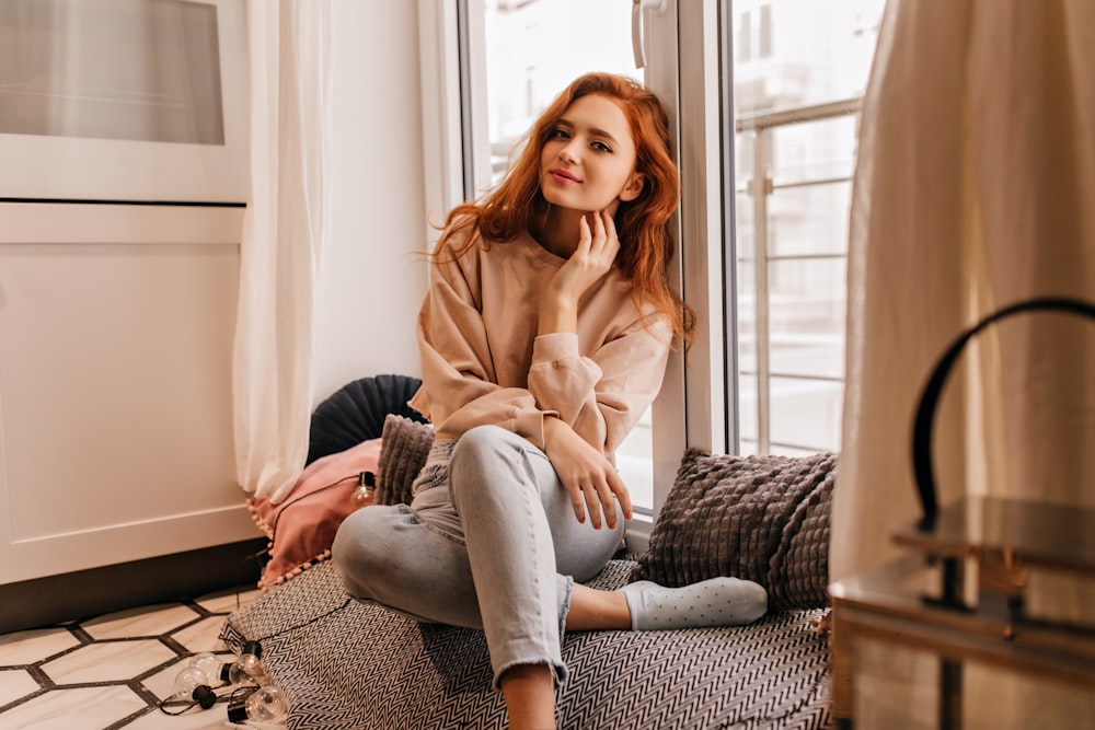 a woman sitting on a couch in front of a window