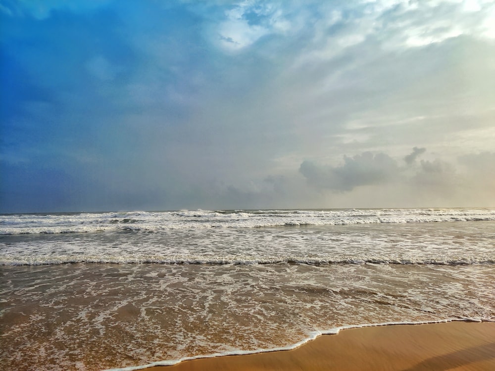 a sandy beach with waves coming in to shore