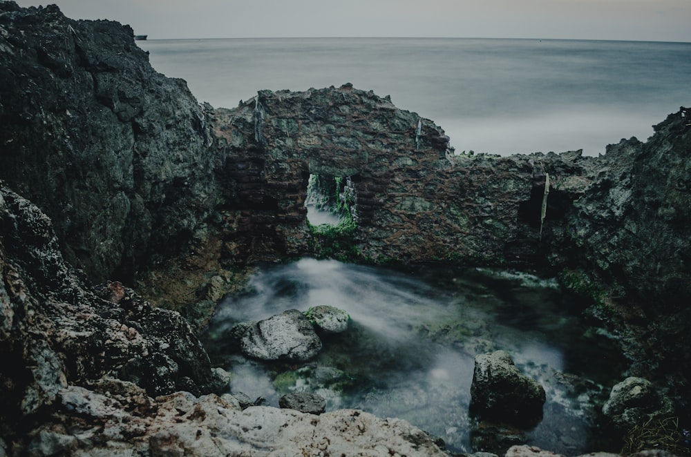 a rocky cliff with a body of water in the middle of it