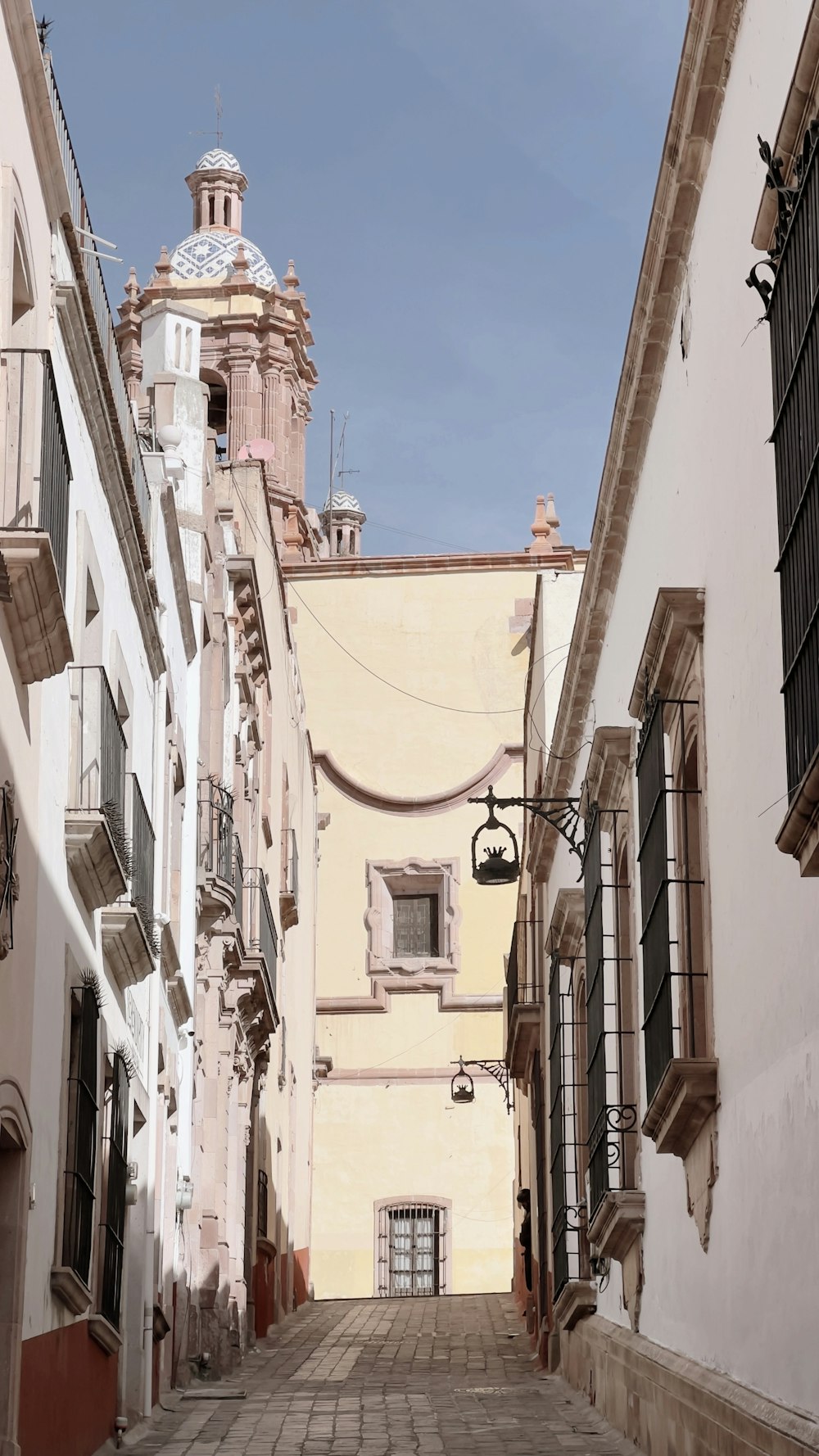 a narrow street with a clock tower in the background