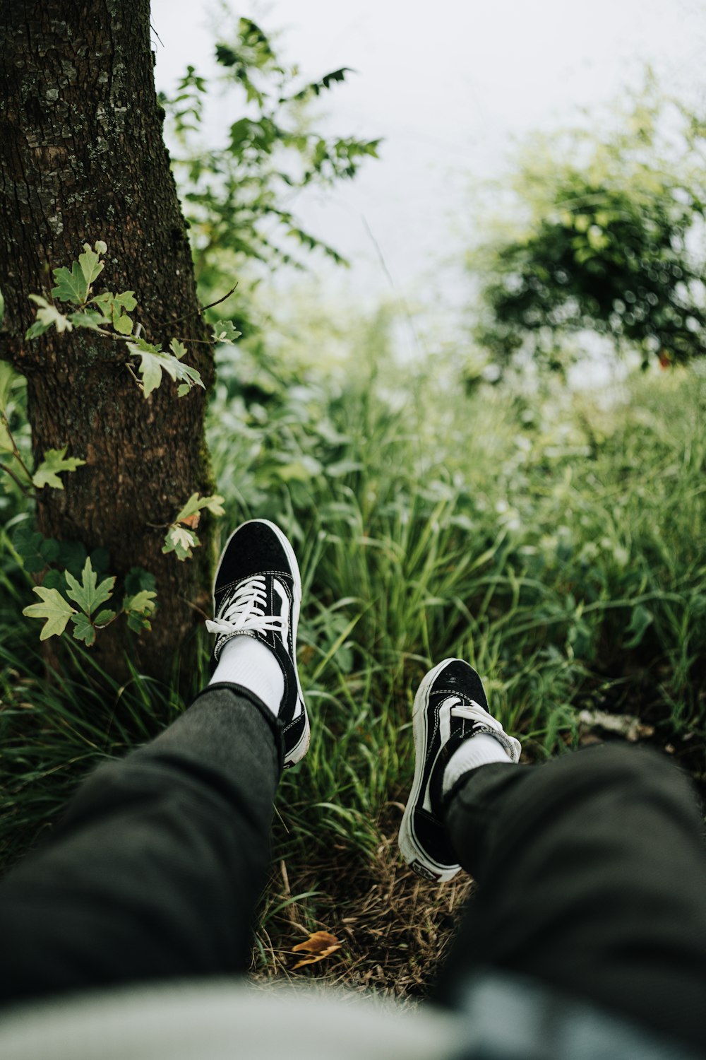 a person wearing black and white shoes standing next to a tree