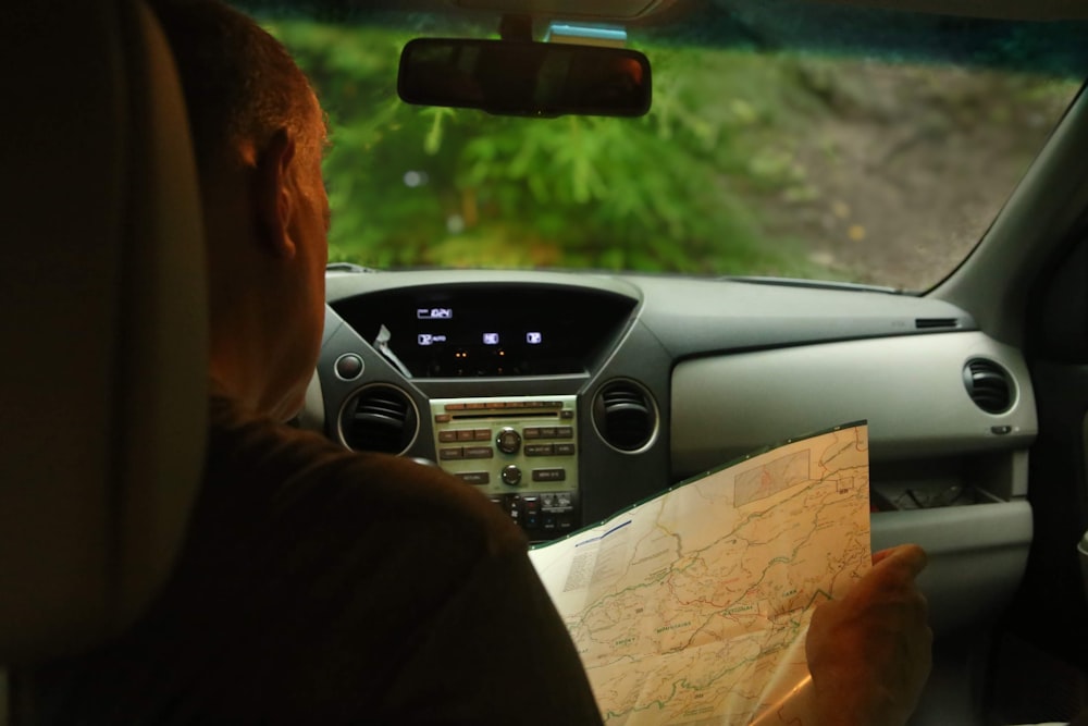 a man sitting in a car looking at a map