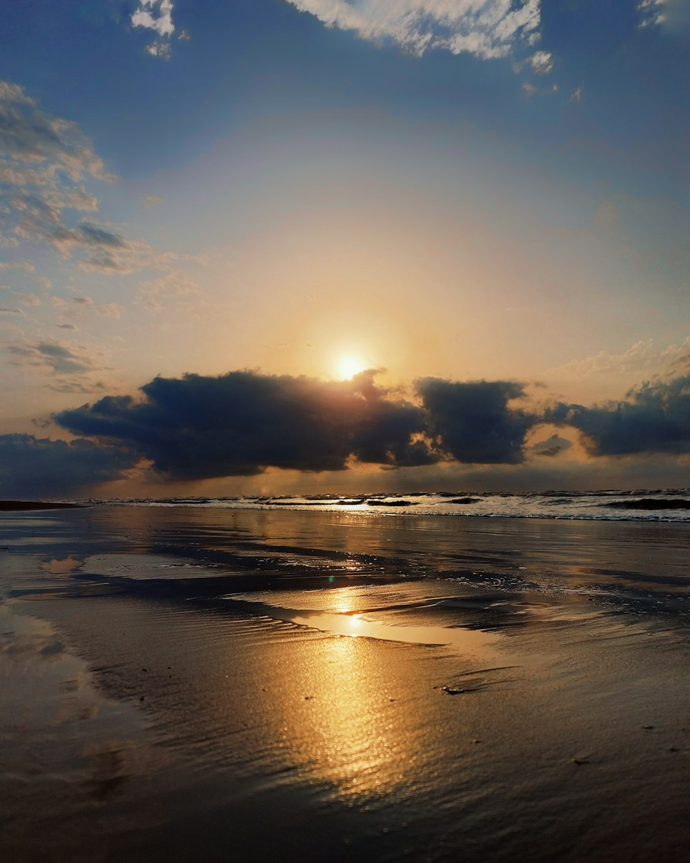 the sun is setting over the water on the beach