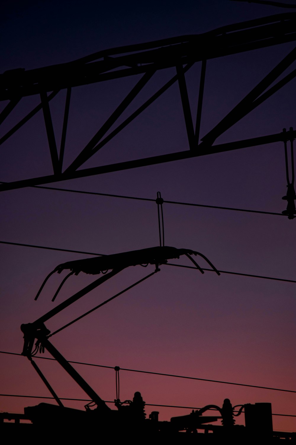 die silhouette von stromleitungen vor einem violetten himmel