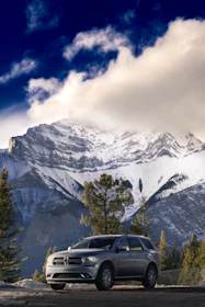 A sleek silver SUV parked on a scenic highway with mountains in the background.