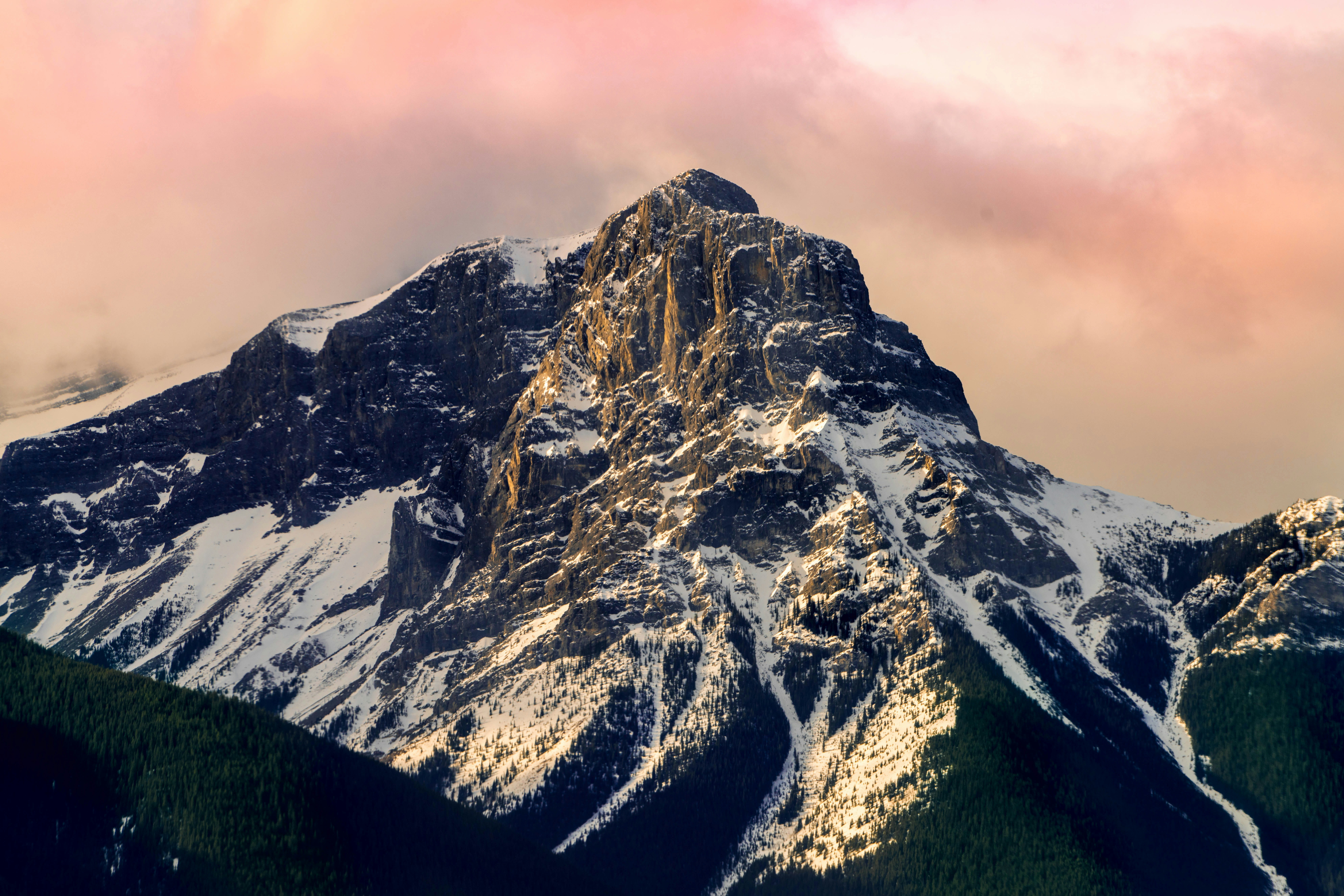 a snow covered mountain with a pink sky in the background