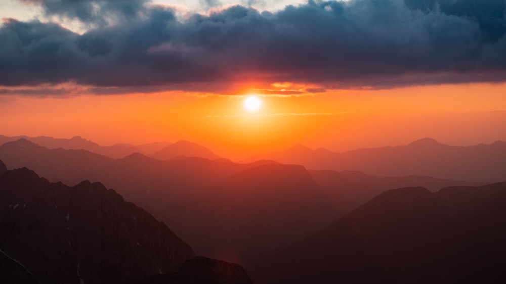 the sun is setting over a mountain range