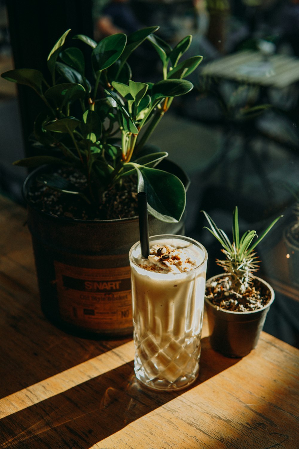 a drink sitting on top of a wooden table next to a potted plant