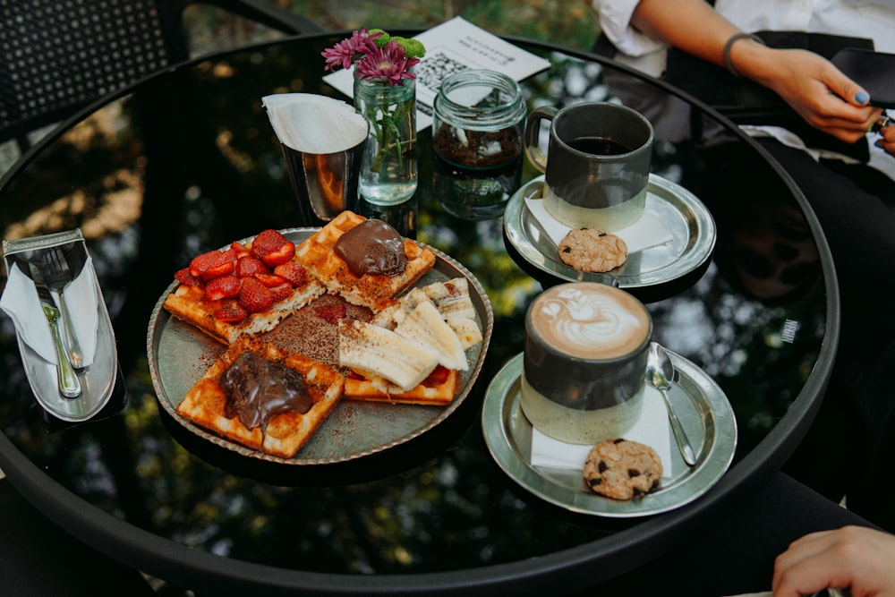 a table topped with plates of food and cups of coffee