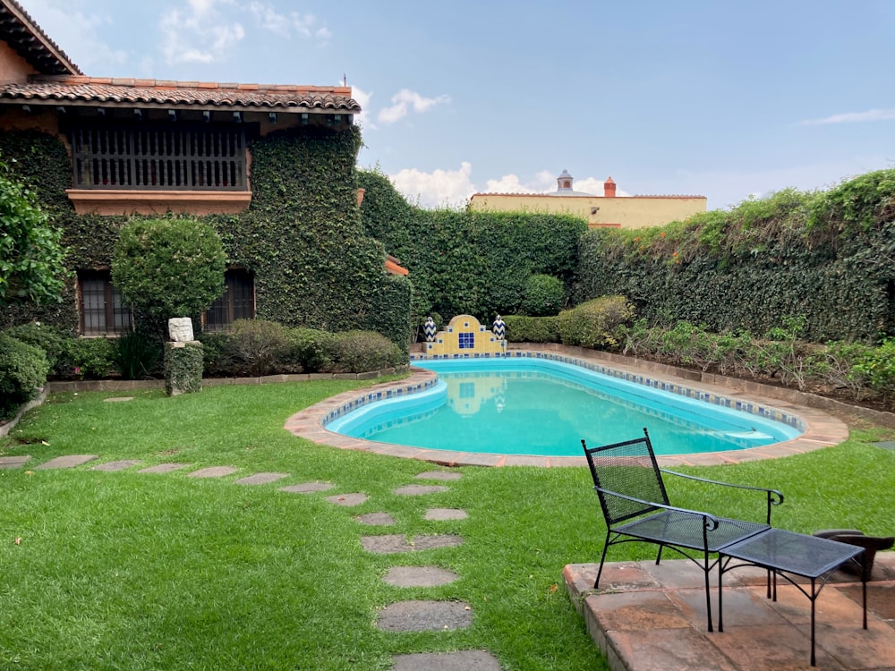 a pool in a yard with a lawn chair next to it